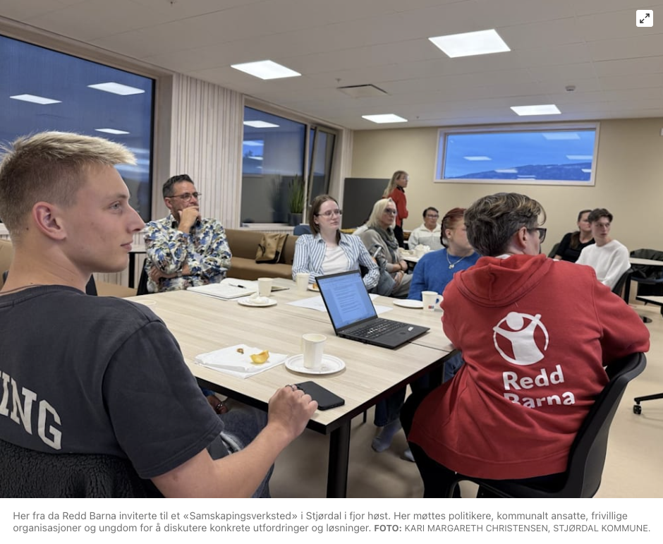 Bildet viser en gruppe mennesker som deltar på et møte i et konferanserom. Flere av deltakerne sitter rundt et bord med notatblokker, kopper, og en bærbar datamaskin. Personene er oppmerksomme og ser engasjerte ut i en diskusjon. «KI-generert bildetekst, kvalitetssikret før publisering.» 