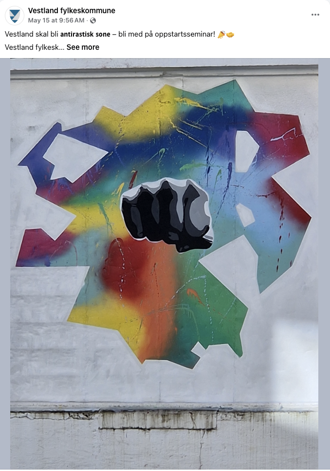 Bildet viser en vegg med gatekunst som består av en knyttneve i svart og hvitt, omgitt av en bakgrunn av regnbuefarger og abstrakte former. «KI-generert bildetekst, kvalitetssikret før publisering.»