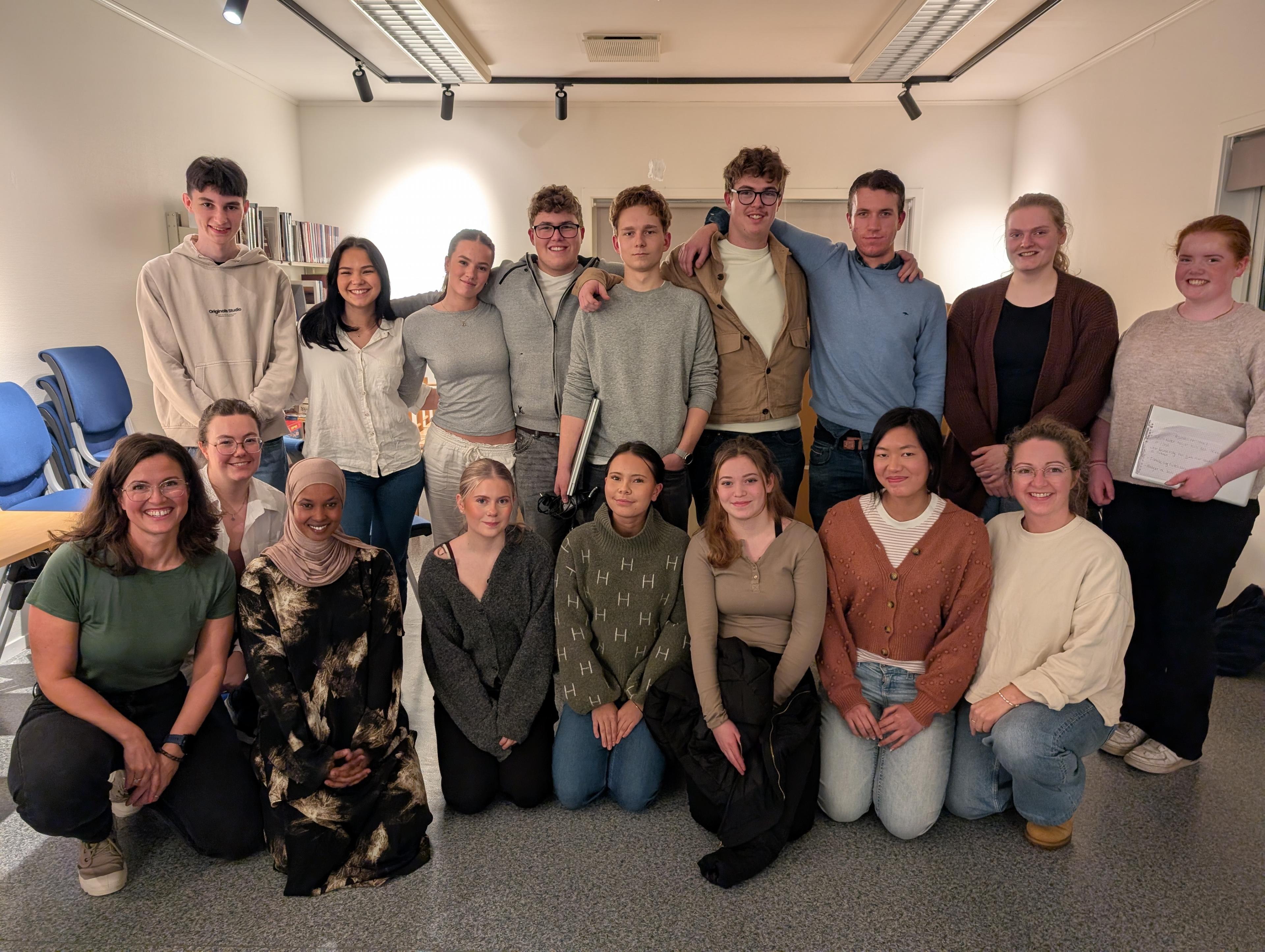 Bildet viser en gruppe mennesker som poserer sammen i et innendørs rom. De smiler mot kameraet og virker vennlige og glade. Det er både stående og sittende personer i bildet, og rommet ser ut som en møte- eller gruppesamlingsplass.«KI-generert bildetekst, kvalitetssikret før publisering.»