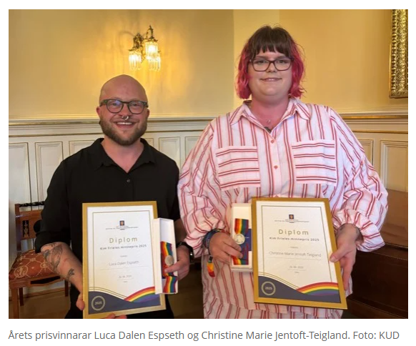 To personer står innendørs, hver holder et diplom. Begge smiler foran en dekorativ bakgrunn.  «KI-generert bildetekst, kvalitetssikret før publisering.»